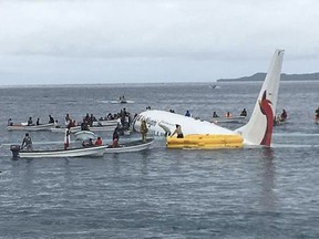In this Sept. 28, 2018, file photo, local fishing boats move in to recover the passengers and crew of Air Niugini flight following the plane crashing into the sea on its approach to Chuuk International Airport in the Federated States of Micronesia.
