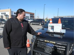 Jaro Giesbrecht looks a photo on display at a mobile command centre set up by police at East Hills Shopping Centre in Calgary on Sunday October 7, 2018.