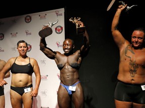 Wes Phills, of Brooklyn, N.Y., center, walks offstage after winning the overall award and middleweight class in the International Association of Trans Bodybuilders competition in Atlanta, Saturday, Oct. 6, 2018. At left are fellow competitors Peter Moore, and Sandy Baird, both of Oakland, Calif., and Kennedy Conners, right, of Conyers, Ga., who took home the heavyweight trophy.