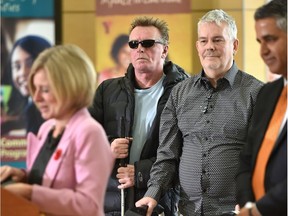 Mark Crichton, left, and Ian Young, centre, listen to Premier Rachel Notley announce details on Thursday, Nov. 8, 2018 of proposed legislation that would help those who receive support from the Assured Income for the Severely Handicapped program.