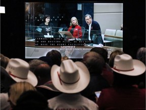 An overflow crowd in the lobby of City Hall watches as Calgary 2026 BidCo's Mary Moran and Scott Scott Hutcheson answer council questions before a vote on a motion to end the 2026 Olympic bid process on Wednesday October 31, 2018. Gavin Young/Postmedia