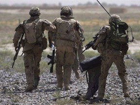 Canadian soldiers help a comrade, center, get on a helicopter after he was injured in an IED blast during a patrol outside Salavat, in the Panjwayi district, southwest of Kandahar, Afghanistan, Monday, June 7, 2010.