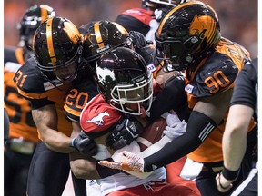 Calgary Stampeders' Don Jackson, front, is tackled by B.C. Lions' Otha Foster III (31), Bo Lokombo (20) and Davon Coleman (90) during the first half of a CFL football game in Vancouver, on Saturday November 3, 2018.