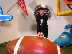 Calgary Stampeders quarterback Bo Levi Mitchell has some fun posing with a giant football during media day at the Grey Cup in  Edmonton on Thursday. (Gavin Young/Postmedia)