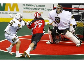 Calgary Roughnecks Zach Currier, middle, collides with Vancouver Warriors Joel McCready, left, as he tries to score on Warriors goalie Aaron Bold during their game at the Scotiabank Saddledome in Calgary, on Saturday December 15, 2018. Leah Hennel/Postmedia