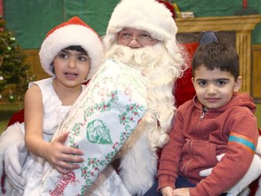 Rawan Al Tamimi, 4 yrs and brother Tamim, 2 1/2 yrs join Santa during the Calgary Fire Department's Annual Chritmas Party at the Stampede Corral in Calgary on Sunday, December 16, 2018. Jim Wells/Postmedia
