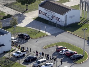 In this Wednesday, Feb. 14, 2018 file photo, students are evacuated by police from Marjory Stoneman Douglas High School in Parkland, Fla., after a shooter opened fire on the campus.