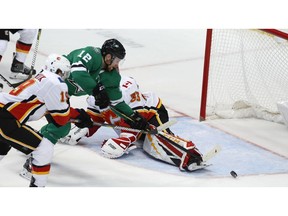 Dallas Stars center Radek Faksa (12) gets the puck past Calgary Flames goaltender David Rittich (33) and Matthew Tkachuk (19) scoring a goal during the second period of an NHL hockey game in Dallas, Tuesday.