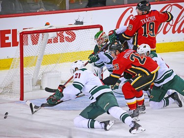 Calgary Flames players Sean Monahan and Matthew Tkachuk scramble for a loose puck with Minnesota Wild players and goaltedender Alex Stalock during NHL action at the Scotiabank Saddledome in Calgary on Thursday December 6, 2018.