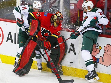 Calgary Flames goaltender Mike Smith deals with the Minnesota Wild's Zach Parise, left and Matt Dumba behind his net during NHL action at the Scotiabank Saddledome in Calgary on Thursday December 6, 2018.