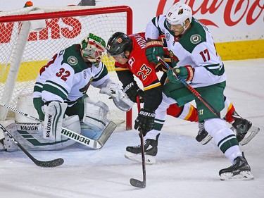 The Calgary Flames' Sean Monahan tangles with Minnesota Wild Marcus Foligno and goaltender Alex Stalock during a scoring chance in NHL action at the Scotiabank Saddledome in Calgary on Thursday December 6, 2018.