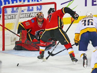 The Calgary Flames Mike Smith and T.J. Brodie deal with a rolling puck along with the Nashville Predators' Zac Rinaldo during NHL action at the Scotiabank Saddledome in Calgary on Saturday December 8, 2018.