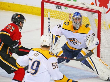 Nashville Predators goaltender Juuse Saros tracks the puck in front of Calgary Flames forward Sean Monahan in NHL action at the Scotiabank Saddledome in Calgary on Saturday December 8, 2018.