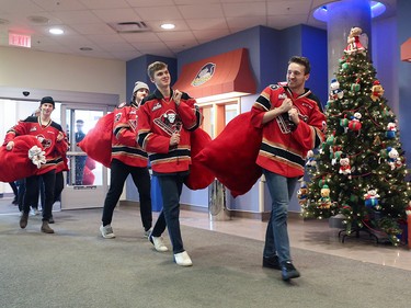 Calgary Hitmen players carry bags full of teddy bears into the Alberta Children's Hospital Monday, December 10, 2018. The team was there to distribute some of the thousands of bears collected at Sunday's annual Brick Teddy Bear Toss game.