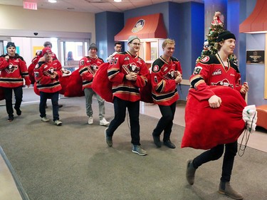 Calgary Hitmen players carry bags full of teddy bears into the Alberta Children's Hospital Monday, December 10, 2018. The team was there to distribute some of the thousands of bears collected at Sunday's annual Brick Teddy Bear Toss game.