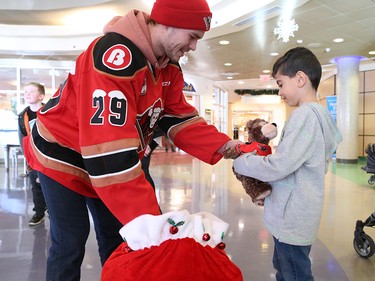 Calgary Hitmen forward Kaden Elder gives a teddy bear to Nawaar Matalka at the Alberta Children's Hospital Monday, December 10, 2018. Hitmen players distributed some of the thousands of bears collected at Sunday's annual Brick Teddy Bear Toss game. Elder scored the first goal in the game to trigger the avalanche of stuffies.