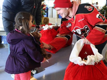 Calgary Hitmen forward Kaden Elder give a teddy bear to Arya Bagnriol, 4, at the Alberta Children's Hospital Monday, December 10, 2018. Hitmen players distributed some of the thousands of bears collected at Sunday's annual Brick Teddy Bear Toss game. Elder scored the first goal in the game to trigger the avalanche of stuffies.