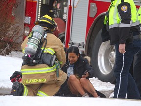 A woman is tended to by firefighters after she was rescued from a burning home in 64th Avenue N.E. on Wednesday, Dec. 12, 2018.