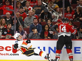 CHICAGO, ILLINOIS - DECEMBER 02: Travis Hamonic #24 of the Calgary Flames hits the ice after colliding with Chris Kunitz #14 of the Chicago Blackhawks at the United Center on December 02, 2018 in Chicago, Illinois. (Photo by Jonathan Daniel/Getty Images)