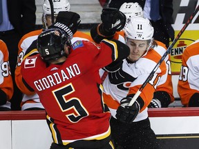 Philadelphia Flyers' Travis Konecny, right, is checked Calgary Flames' Mark Giordano during second period NHL hockey action in Calgary, Wednesday, Dec. 12, 2018.