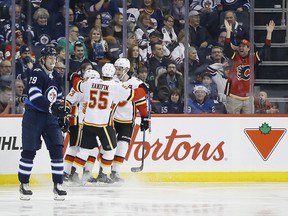 Flames Noah Hanifin, Johnny Gaudreau and Sean Monahan celebrate Gaudreau's goal that went off the stick of Winnipeg Jets right wing Patrik Laine in the second period in Winnipeg on Thursday, Dec. 27, 2018.