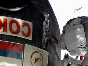 In this image from video made available by NASA, Russian cosmonaut Oleg Kononenko cuts into the insulation on the Soyuz spacecraft attached to the International Space Station on Tuesday, Dec. 11, 2018.
