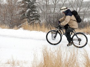 Environment Canada is calling for cloudy skies on Thursday with a 30 per cent chance of flurries in the morning. A Calgary man struggles to ride his bike up the slippery pathway that overlooks the fog covered Bow River and downtown core on March 5, 2012. (Chantelle Kolesnik/Calgary Herald)