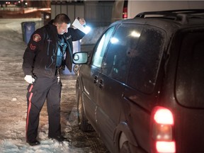 District 5 community resource officer Const. Colin Thorne peeks inside idling vehicles during Operation Cold Start in Calgary, Alta. on Tuesday, Jan. 9 2017. Spearheaded by Thorne, the anti-auto theft program seeks out and educates owners of cars who leave them idling with the keys inside.