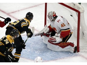 Boston Bruins center Danton Heinen (43) and left wing Jake DeBrusk (74) watch their teammate's goal get by Calgary Flames goaltender Mike Smith (41) in the first period of an NHL hockey game, Thursday in Boston..