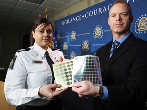 Harpreet Sandhar, Chief of Operations with Canada Border Services Agency and Calgary Police Service Detective Matt Frederiksen display some of the 3,066 counterfeit holographic stickers that were seized by the CBSA and were intended to be used on Canadian and American permanent resident cards. Officials announced the seizure and arrest of a suspect by the Calgary police on Thursday morning January 24, 2019.  Gavin Young/Postmedia