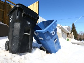 A City of Caglary black bin used to collect garbage and a blue bin for recycling, are shown in an alley in Acadia in Calgary on Saturday, March 10, 2018.