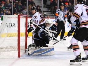 The puck sails past Kootenay Ice goaltender Curtis Meger with the Calgary Hitmen’s Tye Carrier, right, and James Malm near the net during Sunday’s game at the Saddledome.
