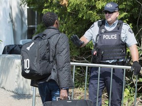 An asylum seekers, claiming to be from Eritrea, is confronted by an RCMP officer as he crosses the border into Canada from the United States Monday, Aug. 21, 2017 near Champlain, N.Y.