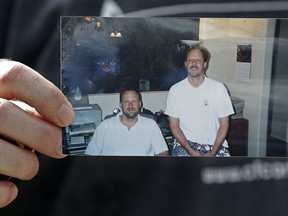 In this Oct. 2, 2017 file photo, Eric Paddock holds a photo of himself, at left, and his brother, Stephen Paddock, at right, outside his home in Orlando, Fla.