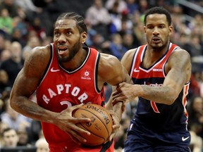 The Wizards' Trevor Ariza fouls Raptors star Kawhi Leonard during double overtime in Washington on Sunday. (Rob Carr/Getty Images)