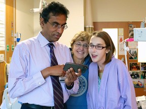 In this Jan. 2, 2019 photo provided by the University of Chicago Medicine, heart transplant surgeon Valluvan Jeevanandam, MD, chief of cardiac surgery at the University of Chicago Medicine, shows triple transplant patient Sarah McPharlin, right, photos on his phone in Chicago.