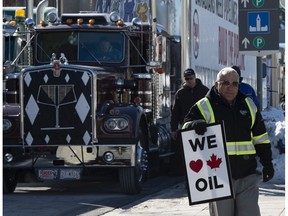 A pro-oil protester stands near convoy vehicles in front of Parliament Hill in Ottawa, Tuesday.
