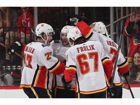 The Calgary Flames celebrate a goal at 13:52 of the second period against the New Jersey Devils by Mark Giordano #5  (2nd from left) at the Prudential Center on Wednesday night in Newark, N.J.