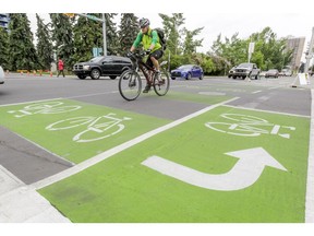 A cyclist crosses 2 St SW on the 12 Ave pilot cycle track in Calgary, Alta., on Tuesday, June 2, 2015. The two-way bicycle lanes were opened for the first time that morning. Lyle Aspinall/Calgary Sun/Postmedia Network