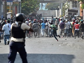 Demonstrators flee as Haitian Police open fire, during the clashes, in the centre of Haitian Capital Port-au-Prince, February 13, 2019. - This is the seventh day of protests against Haitian President Jovenel Moise and the misuse of the Petrocaribe fund. (Photo by HECTOR RETAMAL / AFP)HECTOR RETAMAL/AFP/Getty Images