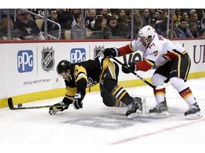Calgary Flames blueliner TJ Brodie (7) checks Pittsburgh Penguins' Bryan Rust (17) off the puck during the second period of an NHL hockey game in Pittsburgh, Saturday, Feb. 16, 2019.