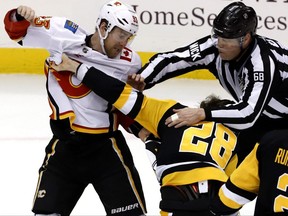 A fight between Pittsburgh Penguins' Marcus Pettersson (28) and Calgary Flames' Sam Bennett (93) is broken up by linesman Scott Driscoll (68) during the first period of an NHL hockey game in Pittsburgh, Saturday, Feb. 16, 2019. (AP Photo/Gene J. Puskar) ORG XMIT: PAGP102