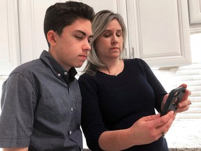 Grant Thompson and his mother, Michele, look at an iPhone in the family's kitchen in Tucson, Ariz., on Thursday, Jan. 31, 2019.