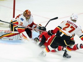 Senators centre Jean-Gabriel Pageau is tripped by Flames defenceman Dougie Hamilton as he skates in on netminder David Rittich, March 9, 2018.