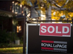 A real estate sold sign hangs in front of a property