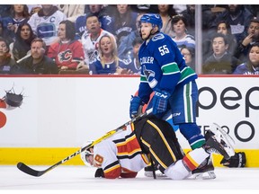 Calgary Flames' James Neal, bottom, holds his mouth after taking a high stick to the face from Vancouver Canucks' Alex Biega (55) and losing teeth during third period NHL hockey action in Vancouver on Saturday, Feb. 9, 2019.