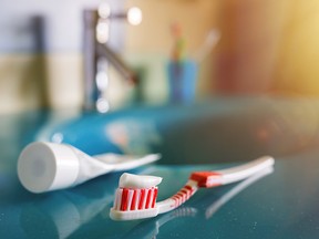 teeth health: brush and toothpaste on blue sink in bathroom. red toothbrush lies in the interior on background of water tap.