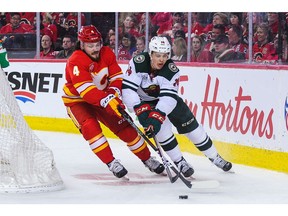 CALGARY, AB - MARCH 2: Rasmus Andersson #4 of the Calgary Flames battles for the puck against Joel Eriksson Ek #14 of the Minnesota Wild during an NHL game at Scotiabank Saddledome on March 2, 2019 in Calgary, Alberta, Canada.