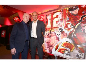 Lanny McDonald (L) and Jarome Iginla greet each other  and pose in front of a painting by artist David Arrigo during a luncheon and media conference in Calgary at the Saddledome Friday, March 1, 2019. Iginla's jersey will be retired at a pre-game ceremony on Saturday night. Jim Wells/Postmedia