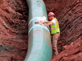 A pipe fitter lays Enbridge pipe for crude oil.